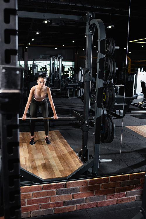 athletic sportswoman training with power rack in sports center