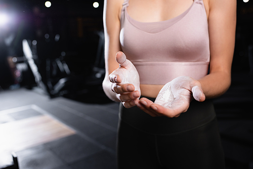 partial view of sportswoman applying talcum powder on hands in sports center