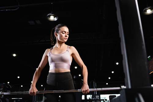 athletic woman in sports bra training with power rack in sports center