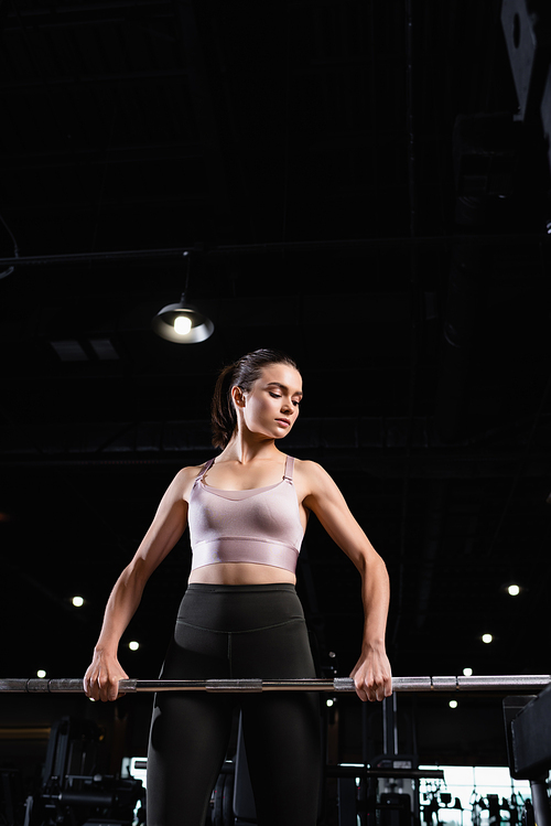 athletic sportswoman in top and leggings working out with power rack in gym