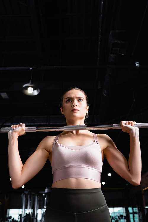 young sportswoman in bra lifting power rack in gym