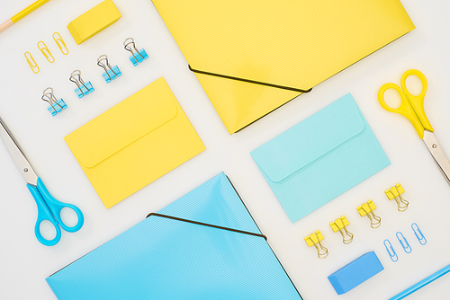 flat lay of blue and yellow folders, envelopes, scissors, pencils, erasers and paper clips isolated on white