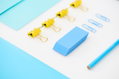 flat lay of blue paper clips, eraser, folder, pencil, envelope and yellow paper clips