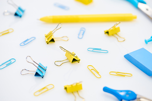 selective focus of colourful paper clips and other stationery on white background