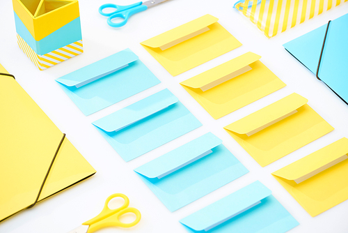 flat lay of colourful envelopes, scissors, folders, pencil case and pencil box on white background