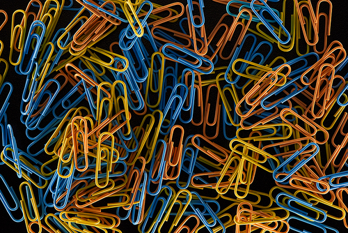 top view of colourful paper clips isolated on black