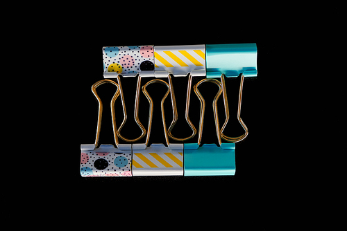 top view of yellow, blue and textured paper clips isolated on black