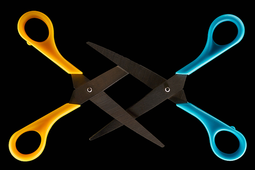 top view of blue and yellow crossed scissors isolated on black