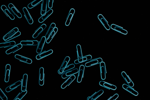 top view of blue scattered paper clips isolated on black