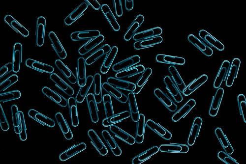 top view scattered blue paper clips isolated on black