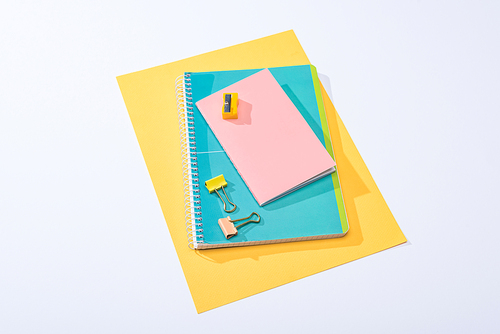 high angle view of notebooks, binder clips, sharpener and paper on white background