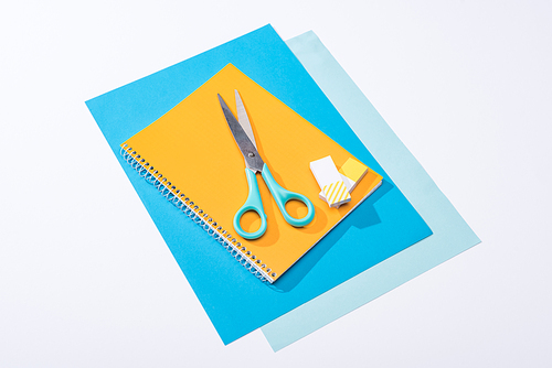 high angle view of scissors, notebook, erasers and paper isolated on white