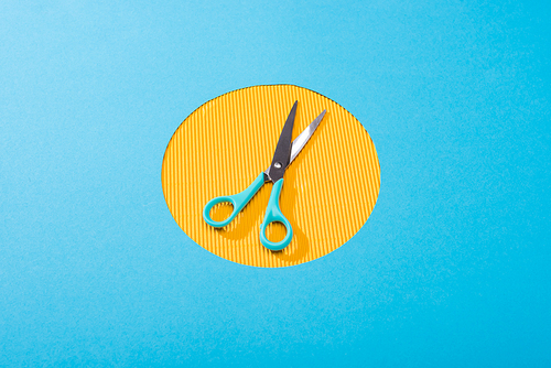 high angle view of metal scissors on yellow circle