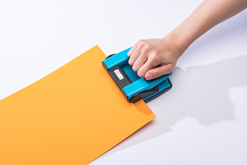 cropped view of woman using holepunch on white background