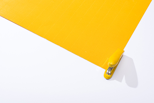 high angle view of stapler and yellow paper on white background