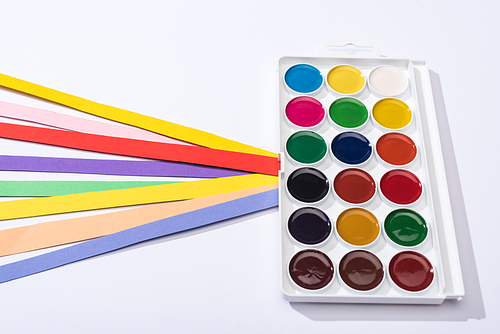high angle view of watercolor and bright paper strips on white background