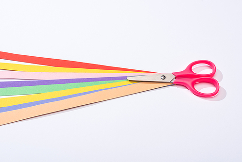 high angle view of scissors and colorful paper strips on white background