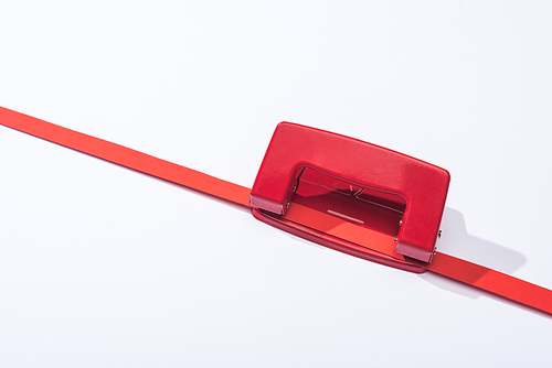 high angle view of red holepunch and paper strip on white background