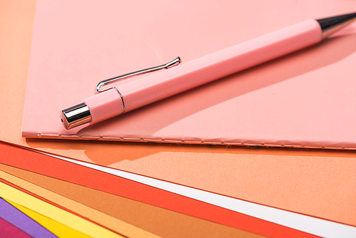 selective focus of pen and notebook on bright and colorful papers