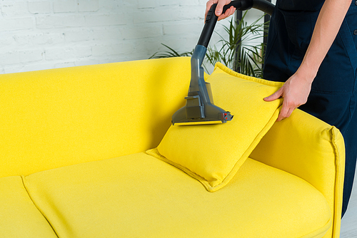 cropped view of man removing dust on pillow with vacuum cleaner