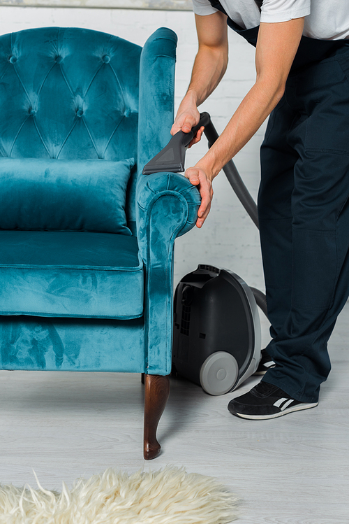 cropped view of cleaner in uniform dry cleaning modern armchair with vacuum cleaner