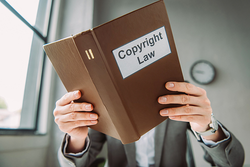 Book with copyright law lettering covering face of female lawyer on blurred background