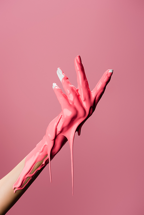 cropped view of hand with dripping paint isolated on pink