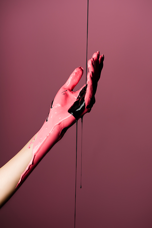 partial view of hand with dripping paint isolated on pink