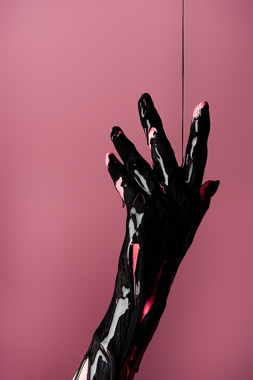 partial view of hand with dripping black paint isolated on pink