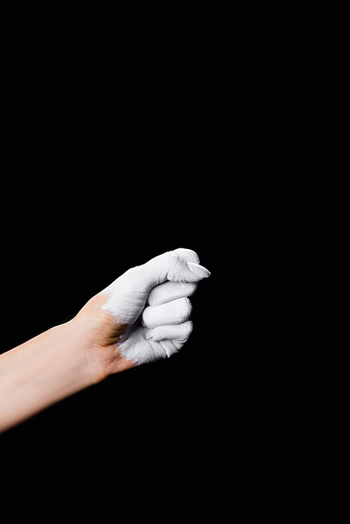 partial view of white painted fist isolated on black