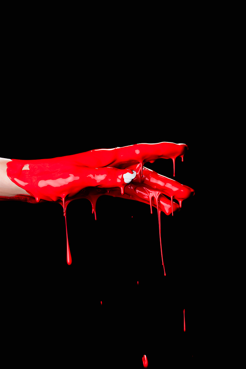 partial view of painted hand with red dripping paint isolated on black