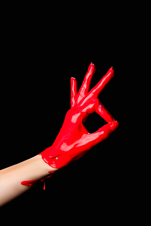 cropped view of hand painted in red paint showing ok sign isolated on black