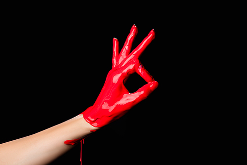 cropped view of hand painted in red paint showing ok sign isolated on black