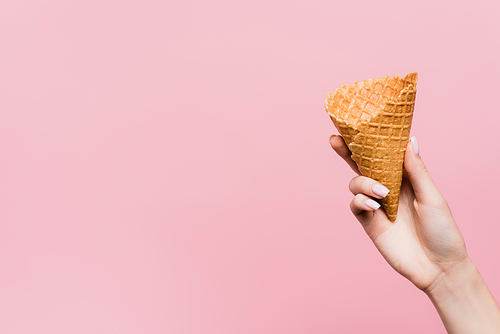 cropped view of woman holding waffle cone isolated on pink