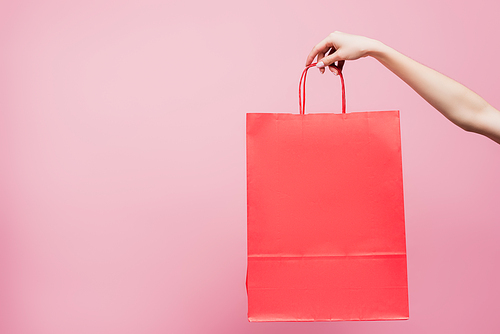 partial view of woman holding shopping bag isolated on pink