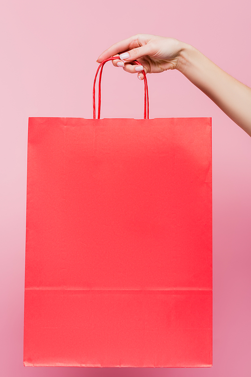 cropped view of woman holding shopping bag isolated on pink