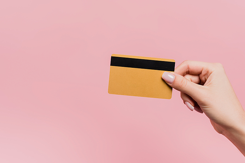 partial view of woman holding credit card in hand isolated on pink