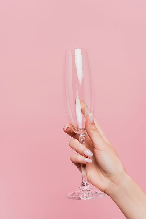 partial view of woman holding empty champagne glass isolated on pink