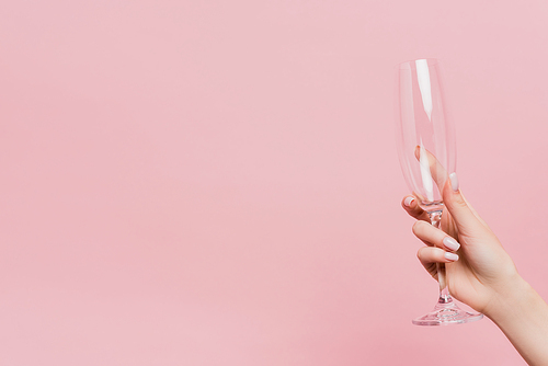 cropped view of woman holding empty champagne glass isolated on pink