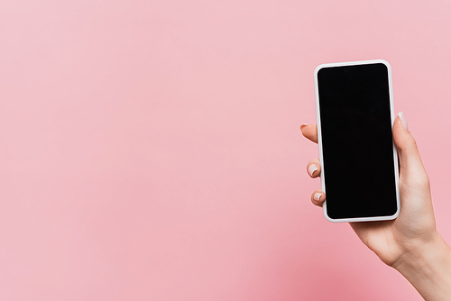 cropped view of woman holding smartphone with blank screen in hand isolated on pink
