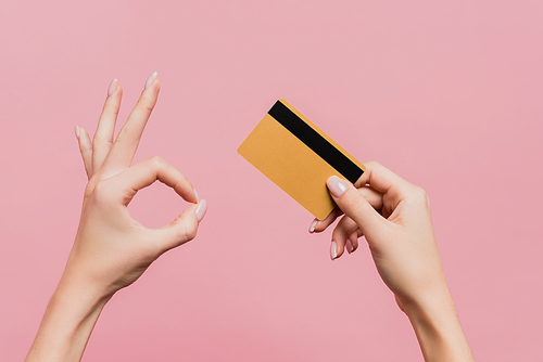 partial view of woman holding credit card and showing ok sign isolated on pink