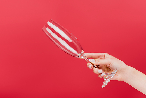 cropped view of woman holding empty champagne glass isolated on red