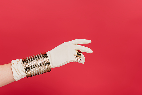 cropped view of woman in glove with rings and bracelet isolated on red