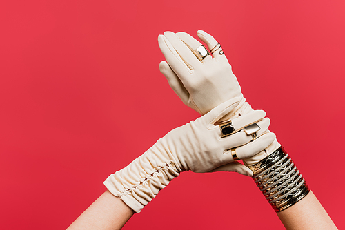 partial view of woman in gloves with rings and bracelet isolated on red