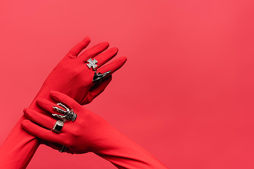 cropped view of female hands in gloves with rings isolated on red