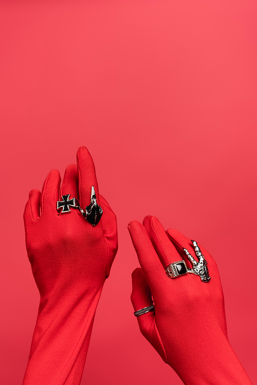 partial view of female hands in gloves with rings isolated on red