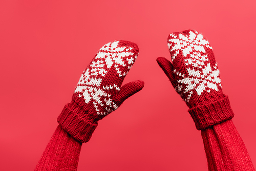 cropped view of female hands in warm mittens isolated on red