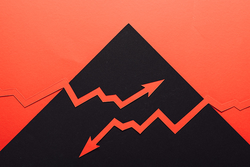 top view of paper cur recession and increase arrows on black and red background