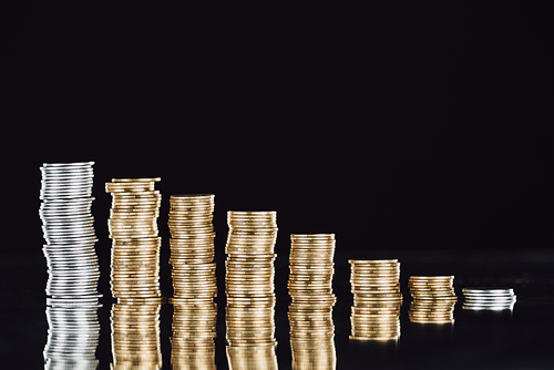 stacks of silver and golden coins on surface with reflection isolated on black