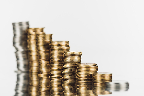 selective focus of stacked silver and golden coins on surface with reflection isolated on white